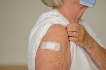 Anonymous lady showing the plaster covering her vaccination site