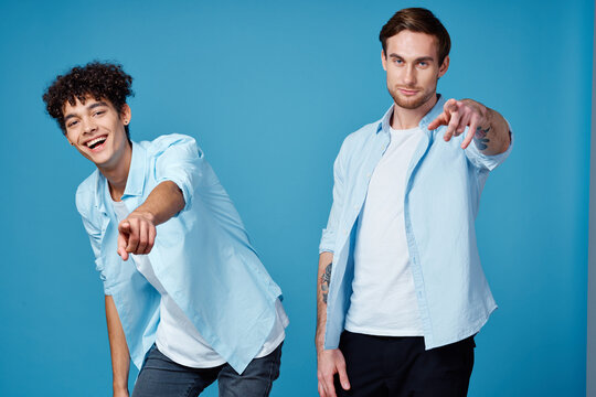 guys in identical shirts and a t-shirt on a blue background friends gesticulate with their hands