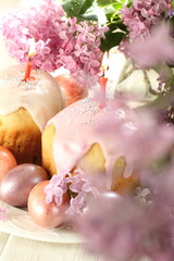 Painted eggs, cakes with glaze and a bouquet of lilacs