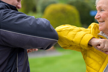 Senior lady greeting a friend by presenting an elbow