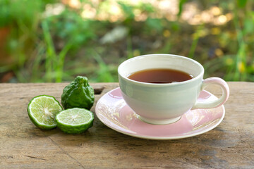 Bergamot tea or Earl Grey tea in white cup and fresh bergamot fruit with sliced on wooden table and blur background.