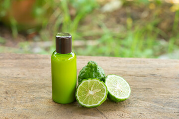 Shampoo made of bergamot in green plastic bottle and fresh bergamot fruit and sliced wooden table wit blur background. Natural products used to care for hair and scalp concept.