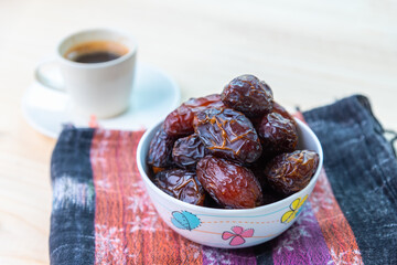 Raw and organic Medjool date fruit eat with black hot espresso coffee.