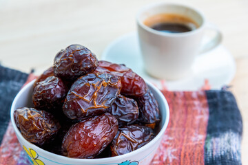 Raw and organic Medjool date fruit eat with black hot espresso coffee.