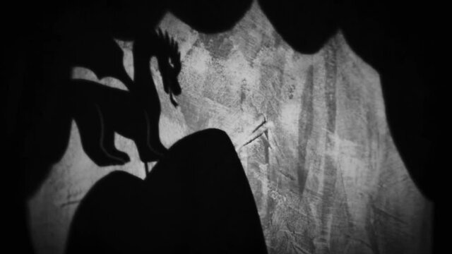 Vintage animation, shadow theatre on a wall. Pantomime, fantasy story. Halloween scene, black and white storytelling. Classic fable for children, creepy puppets.
