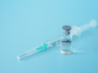Close up, vaccine vial and syringe on blue background, with copy space. Concept of coronavirus outbreak.