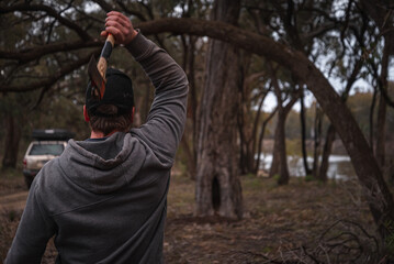 Rearview of Man Throwing axe to a Tree in a Riverside. Lifestyle and Nature Concept