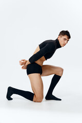 Obraz premium a sexy guy with pumped up muscles stands on his knee on a light background in full growth