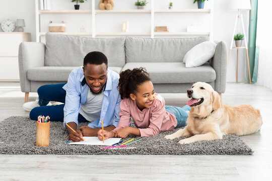 Happy black family drawing with dog at home