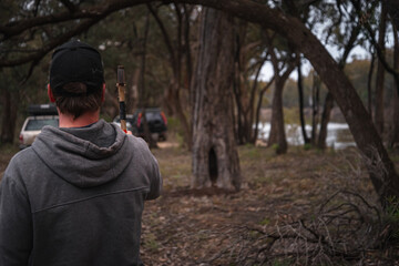 Rearview of Man Throwing axe to a Tree in a Riverside. Lifestyle and Nature Concept