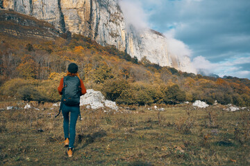 Obraz premium woman in jeans boots and a sweater with a backpack are resting in the autumn in the mountains in nature