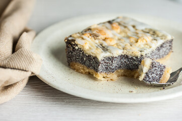 A slice of a poppy cake on a white surface, a close-up