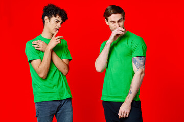 Cheerful friends in green t-shirts gesturing with hands emotions