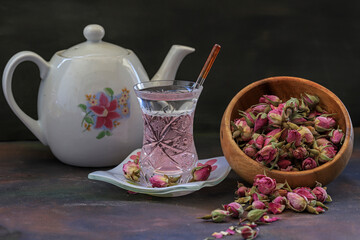 Small rose buds, porcelain teapot and rose tea.