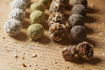 Homemade vegan peanut energy chocolate candy truffles with matcha, chia seeds, almonds and coconut flakes topping
