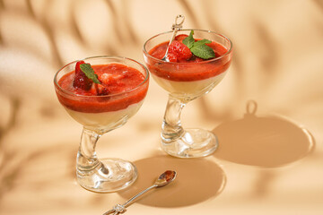 Two glasses of traditional italian creamy pudding dessert panna cotta with peppermint, strawberry...
