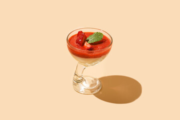 A glass of traditional italian creamy pudding dessert panna cotta with peppermint, strawberry jam, fresh strawberries with hard light shadow