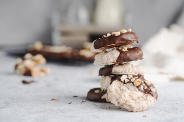 Almond half-chocolate biscuits sprinkled with chopped peanuts and placed on top of each other and milk bottle on light background