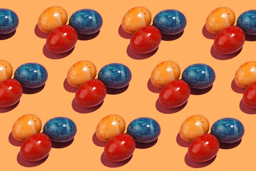 A hard light pattern of three colored easter eggs on an orange background
