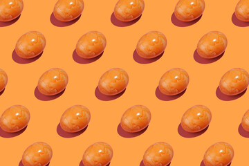 A hard light pattern of an orange colored easter egg on an orange background