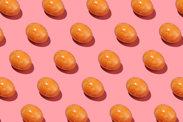 A hard light pattern of an orange colored easter egg on pink background
