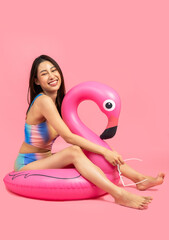 Obraz na płótnie Canvas Beautiful, Sexy asian woman in bikini and smiling standing on pink background isolated .Summer vocation happy trip concept.