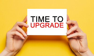 Female hands hold card paper with text Time to upgrade on a yellow background. Business and finance...