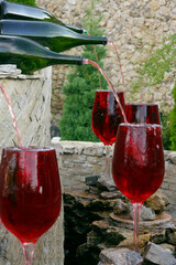 Decorative fountain with red wine pouring from a bottle into a glass.