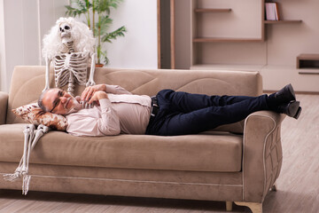 Old man sitting on the sofa with the female skeleton