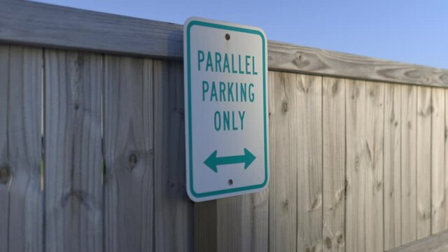 Parallel parking only sign on wooden fence with blue sky as background