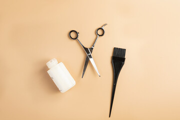 Scissors, hair dye brush and hair mask: instruments for hairdresser on pastel yellow background