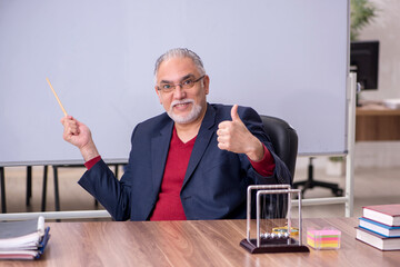 Old teacher physicist sitting in the classroom