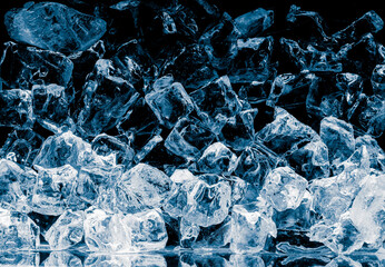 Pieces of crushed pure ice cubes on dark blue background.