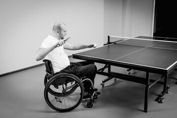 Adult disabled men in a wheelchair playing table tennis