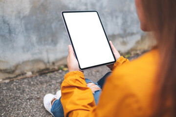Mockup image of a woman holding digital tablet with blank white desktop screen in the outdoors