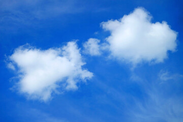 Fluffy white cumulus clouds floating on vibrant blue sky	