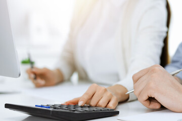 Bookkeeper checking balance with calculator, close-up of hands. Tax and audit concepts