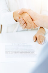 Casual dressed businessman and woman shaking hands after contract signing in sunny office. Handshake concept
