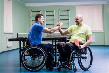 Fototapeta na wymiar Disabled adult men shaking hands after playing table tennis
