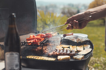 Fototapeta premium BBQ on weekend. Sausages, steak, cheese and vegetables on gas grill. Outdoors.