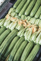 Close up shot of beautiful vegetables on display in vendor's stall in fruit market in italy. beautiful courgettes with orange flowers.