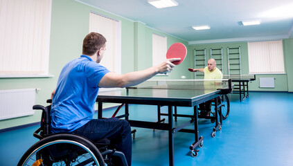 Adult disabled men in a wheelchair playing table tennis