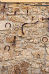 Various old homemade utensils along with rusty tools used in agriculture hanging on the exterior wall of a dwelling