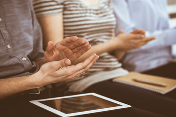 Obraz na płótnie Canvas Business people clapping at meeting or conference, close-up of hands. Group of unknown businessmen and women in modern white office. Success teamwork, corporate coaching and applause concept