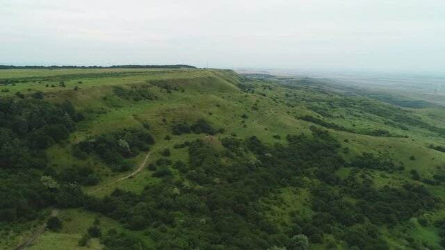 Flight over a green forest hill in the evening