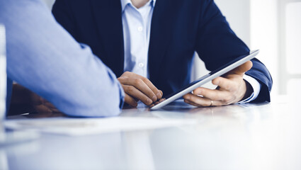 Business people using tablet computer while working together at the desk in modern office. Unknown businessman or male entrepreneur with colleague at workplace. Teamwork and partnership concept