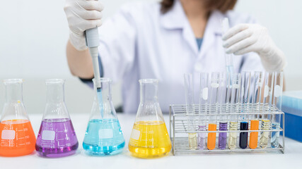 A young woman researcher, doctor, scientist, or laboratory assistant working with plastic medical tubes to research, examine scientific experiments in a modern laboratory. Education stock photo