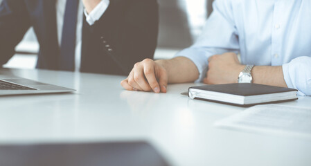 Unknown business people using laptop computer at the desk in modern office. Businessman or male entrepreneur is working with his colleague. Teamwork and partnership concept