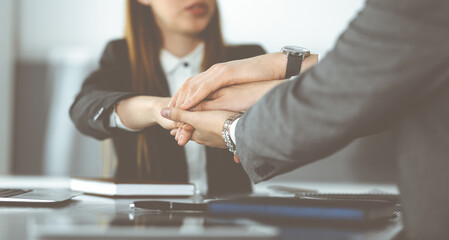 Unknown business people group joining hands in modern office. Businessmen and women making circle with their hands as a team, close-up