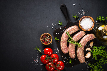 Bratwurst or sausages on cutting board with spices at black table. - obrazy, fototapety, plakaty